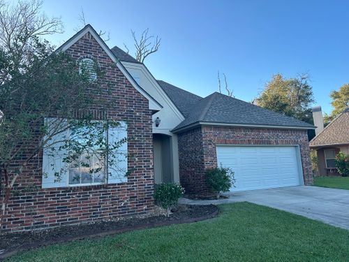 A brick house with a white garage door and a blue sky in the background.