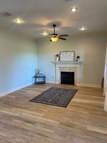 A living room with a fireplace and a ceiling fan.