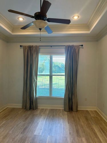 An empty room with a ceiling fan and a window.