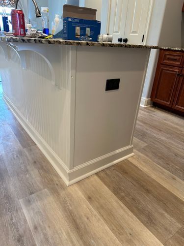 A kitchen with a white island and wooden floors.