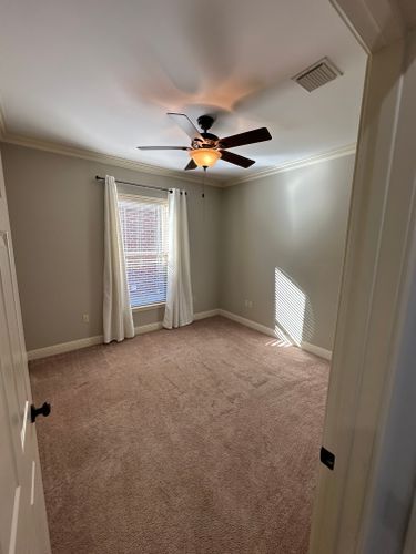An empty bedroom with a ceiling fan and a window.