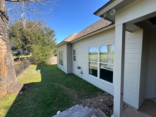 A white house with a lot of windows is sitting on top of a lush green field.