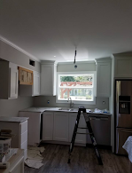 A kitchen with white cabinets and a ladder in the middle of the room.
