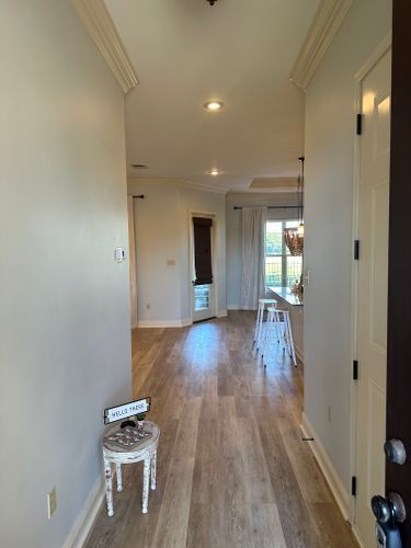 A hallway with hardwood floors and a chair in the middle of it.