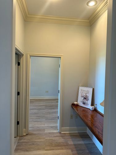 A hallway with a wooden desk and a picture on the wall.