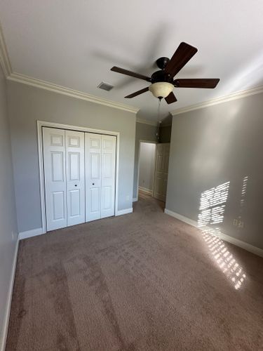 An empty bedroom with a ceiling fan and a closet.