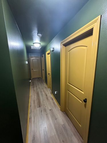 A long hallway with yellow doors and green walls.