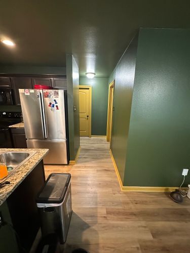 A kitchen with a stainless steel refrigerator , sink , and trash can.
