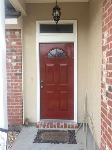 A red door with a brick wall behind it