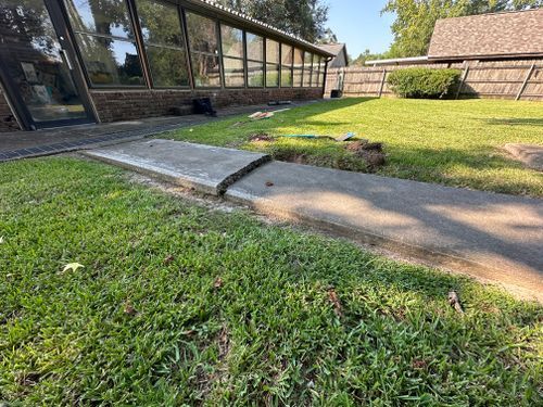 There is a concrete walkway in the grass in front of a building.