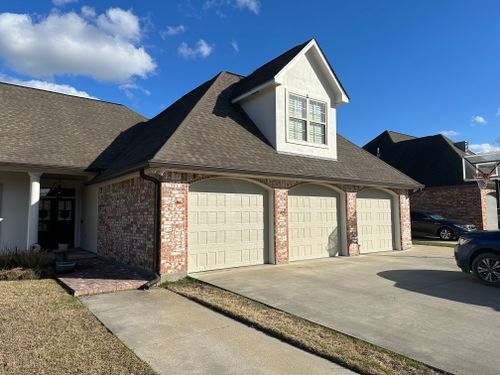 A house with three garage doors and a car parked in front of it.
