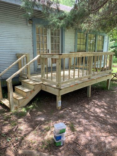 A wooden deck with stairs is sitting in front of a house.