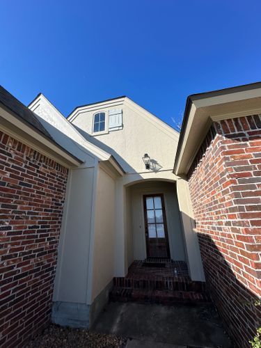 The front door of a brick house with a blue sky in the background.
