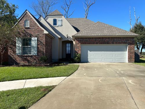 A brick house with a white garage door and a concrete driveway.