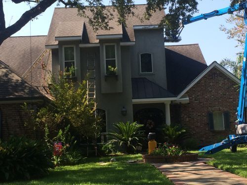 A brick house with a blue crane in front of it.