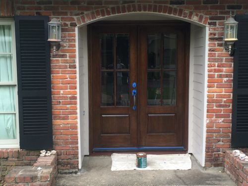 A brick house with a wooden door and black shutters.