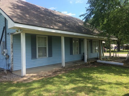 A blue house with a porch and shutters on a sunny day.