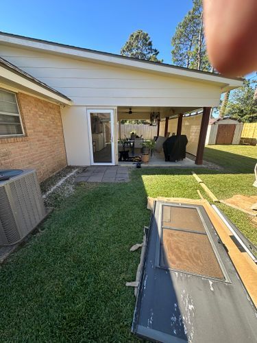 A person is holding a piece of wood in front of a house.