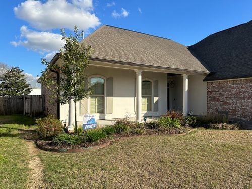 A white house with a porch and a sign in front of it.