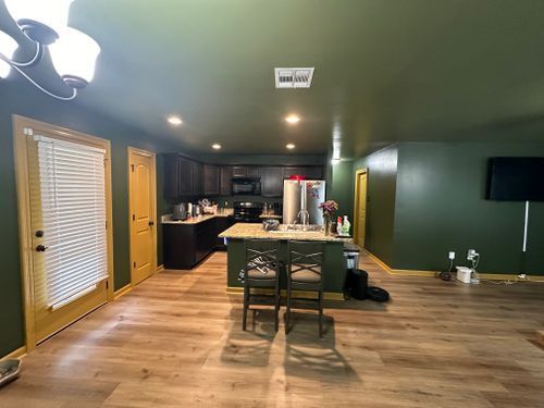 A kitchen with green walls and a wooden floor.