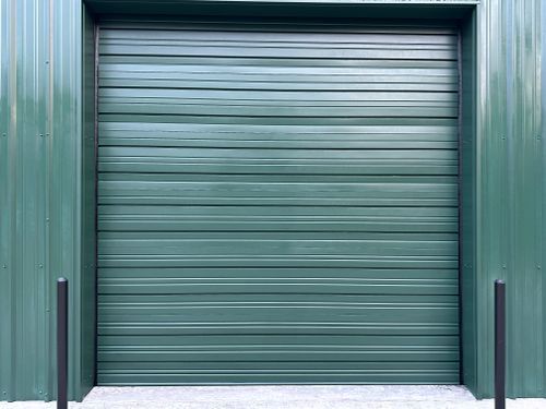 A green garage door is sitting in front of a green building.