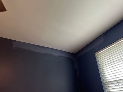 A room with blue walls and white blinds and a ceiling fan.
