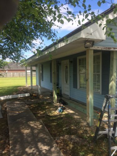 A blue house with a porch and a ladder in front of it.