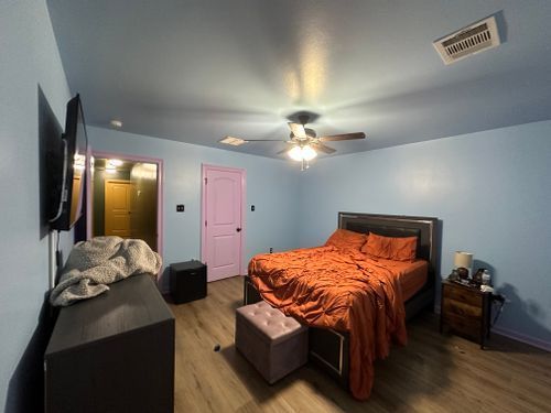 A bedroom with a bed, dresser, nightstand , television and ceiling fan.