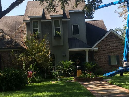 A large brick house with a blue crane in front of it.