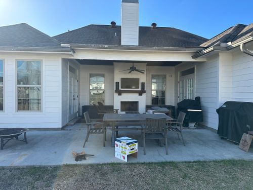 A patio with a table and chairs and a fireplace in the backyard of a house.