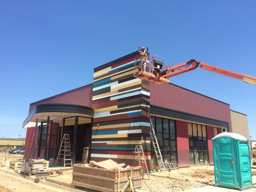 A crane is being used to paint the side of a building.
