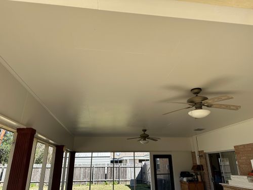 A living room with a ceiling fan and a lot of windows.