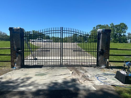 A black metal gate is open to a driveway.