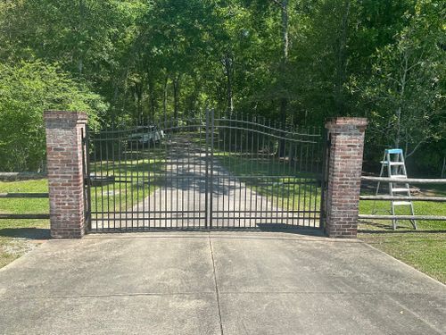 A metal gate with a brick pillar in front of it.