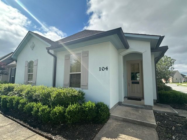 Light blue house with number 104, light shutters, and a dark roof.