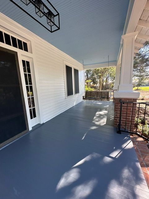 Covered porch with white siding, blue ceiling, and gray floor. Brick pillars and a dark screen door are visible.