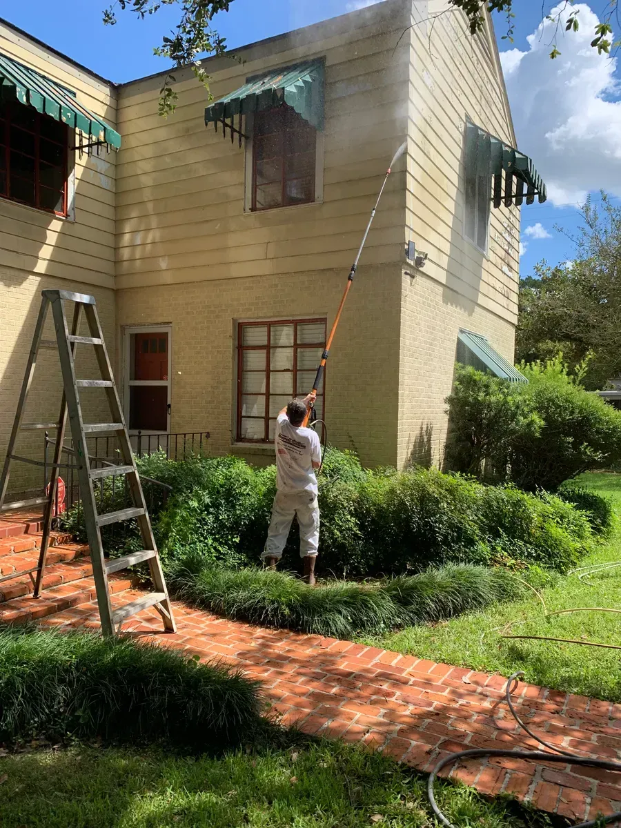 A man is using a high pressure washer to clean a wooden deck.