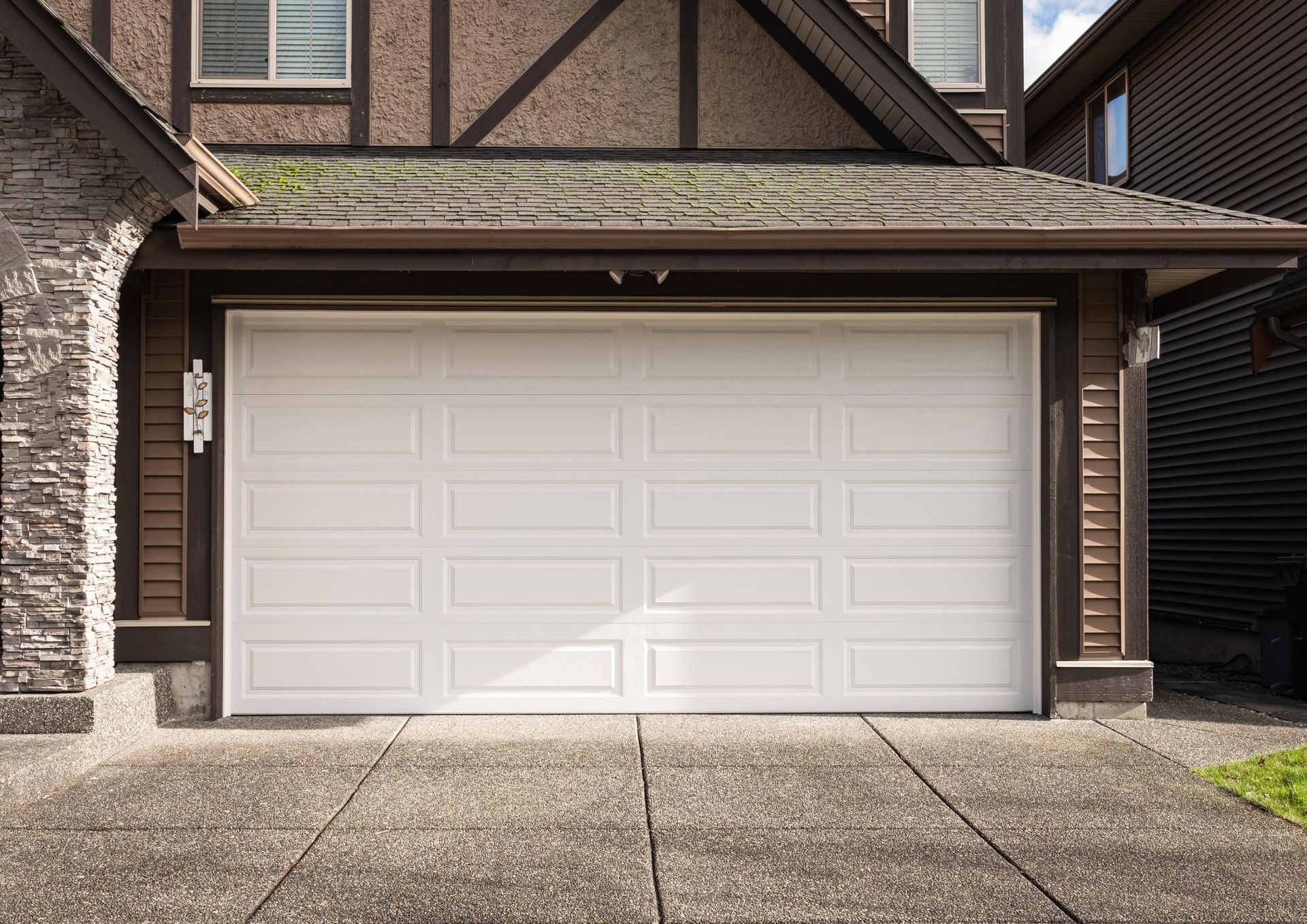 A white garage door is open in front of a house.