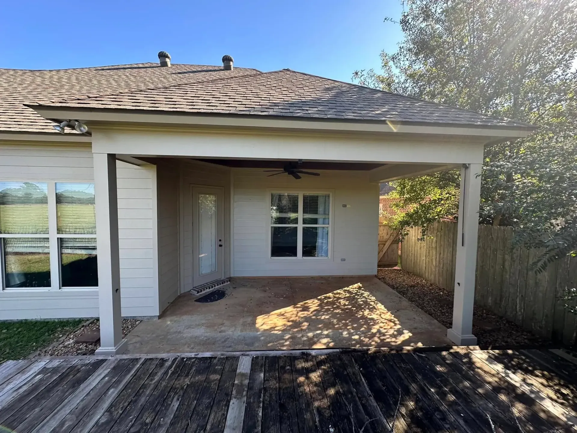 A white house with a covered patio and a ceiling fan.