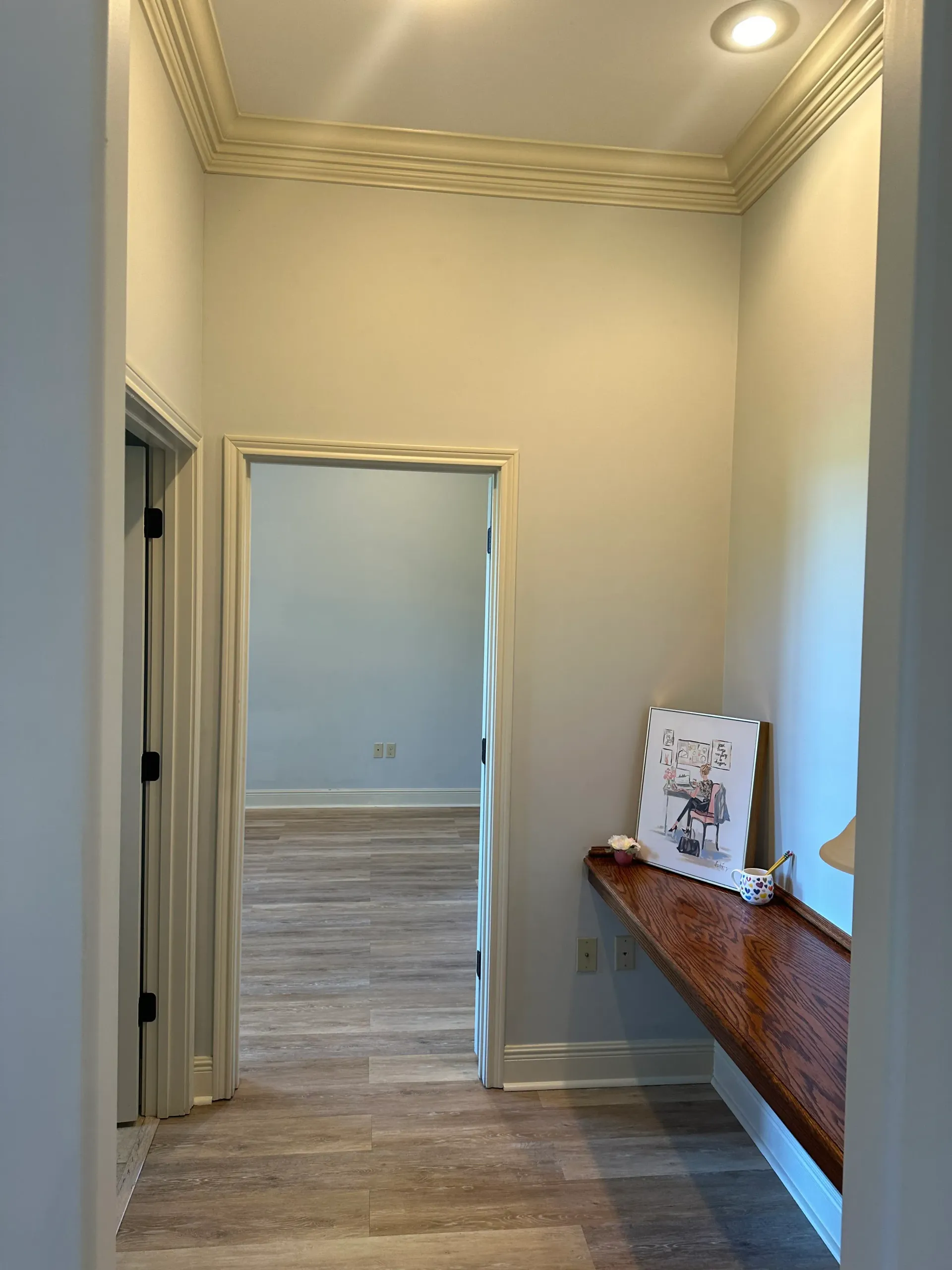 A hallway with a wooden desk and a picture on the wall.