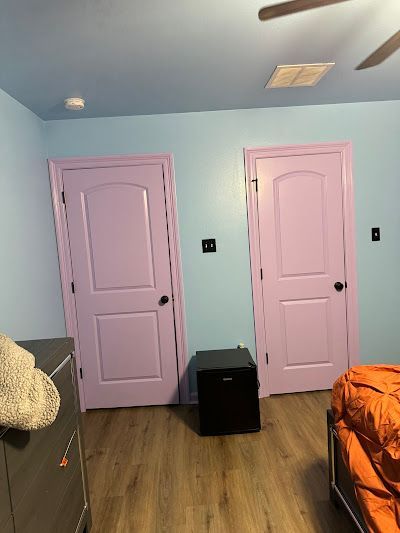 A bedroom with pink doors and blue walls