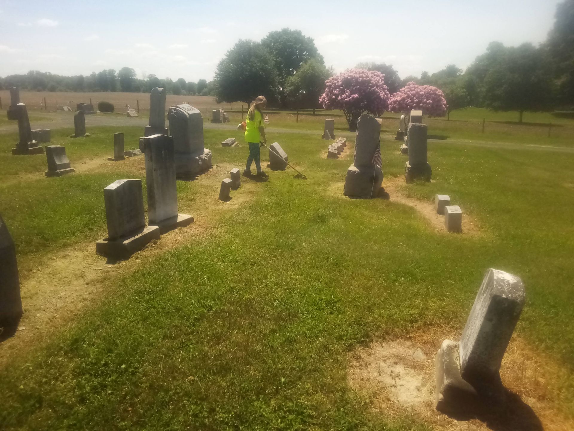A man in a yellow vest is standing in a cemetery