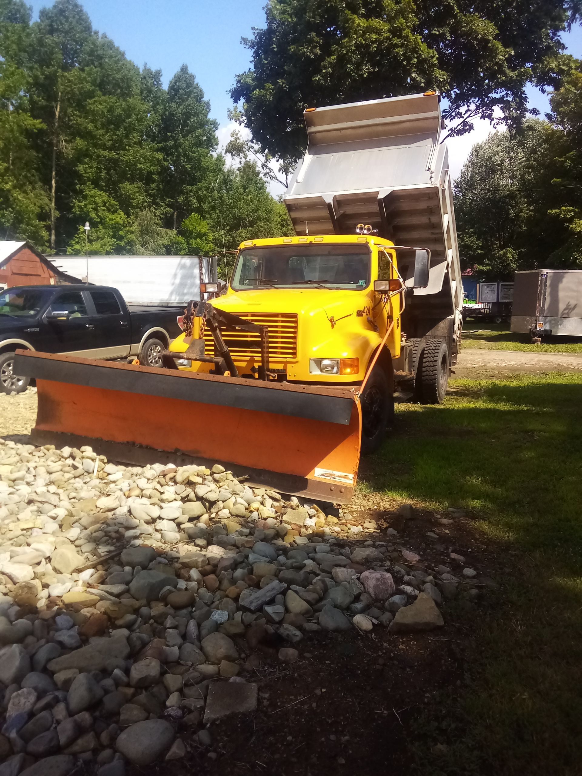 A yellow dump truck with a snow plow attached to it