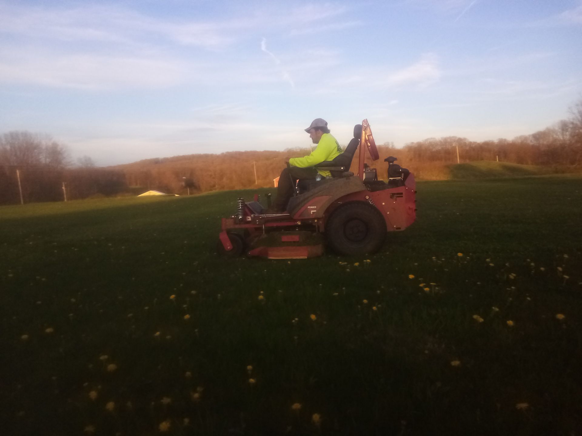 A man is riding a lawn mower in a field