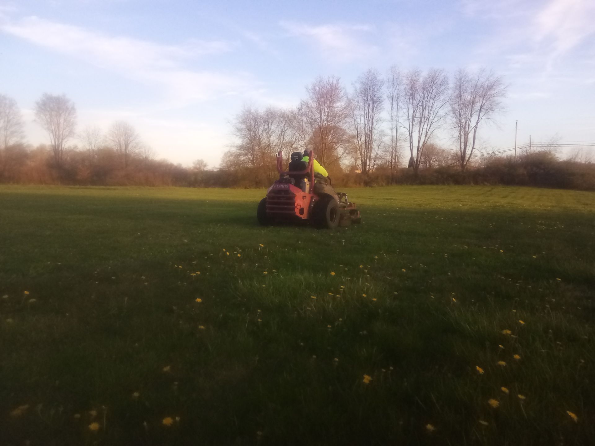 A person is riding a tractor through a grassy field.