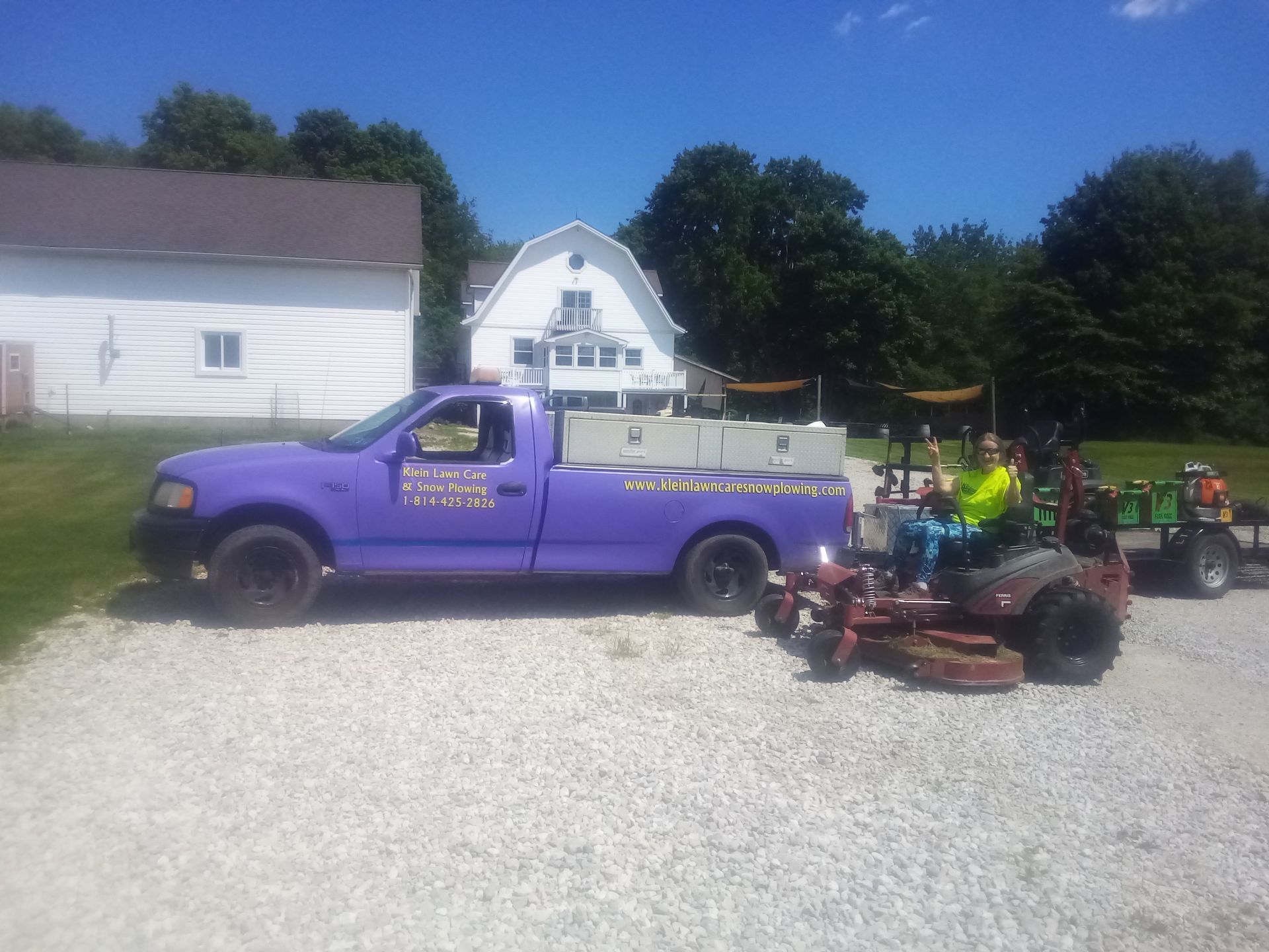 A purple truck is parked next to a lawn mower