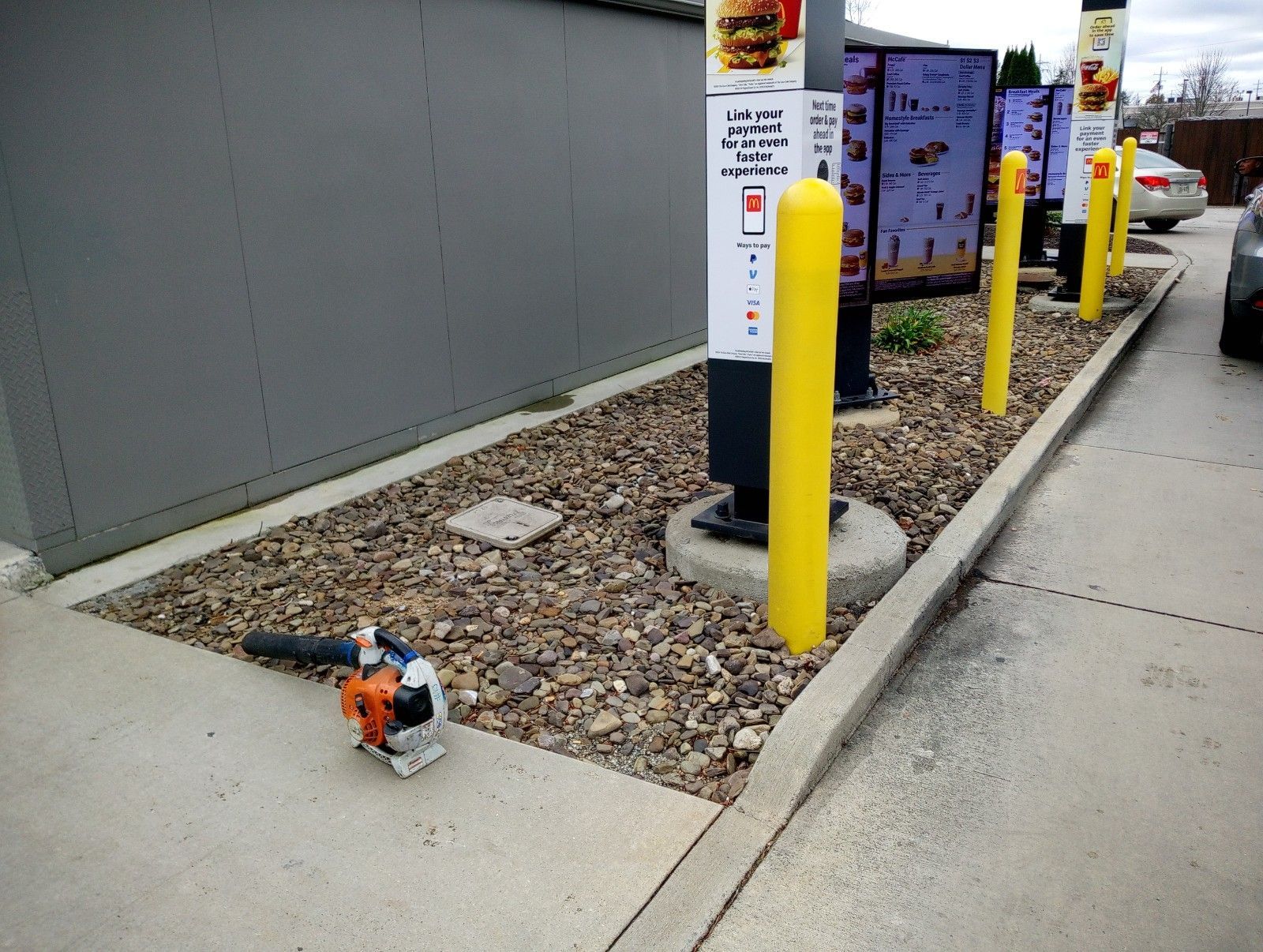 A mcdonald 's drive thru with a lawn mower on the sidewalk