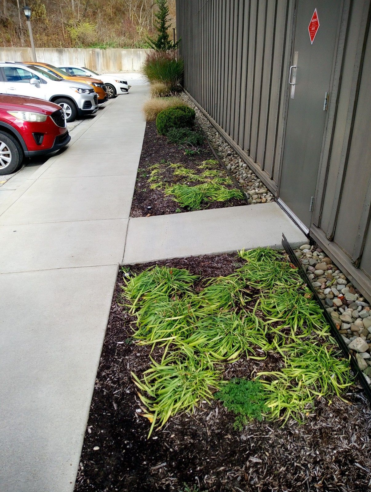A row of cars are parked on a sidewalk next to a building.