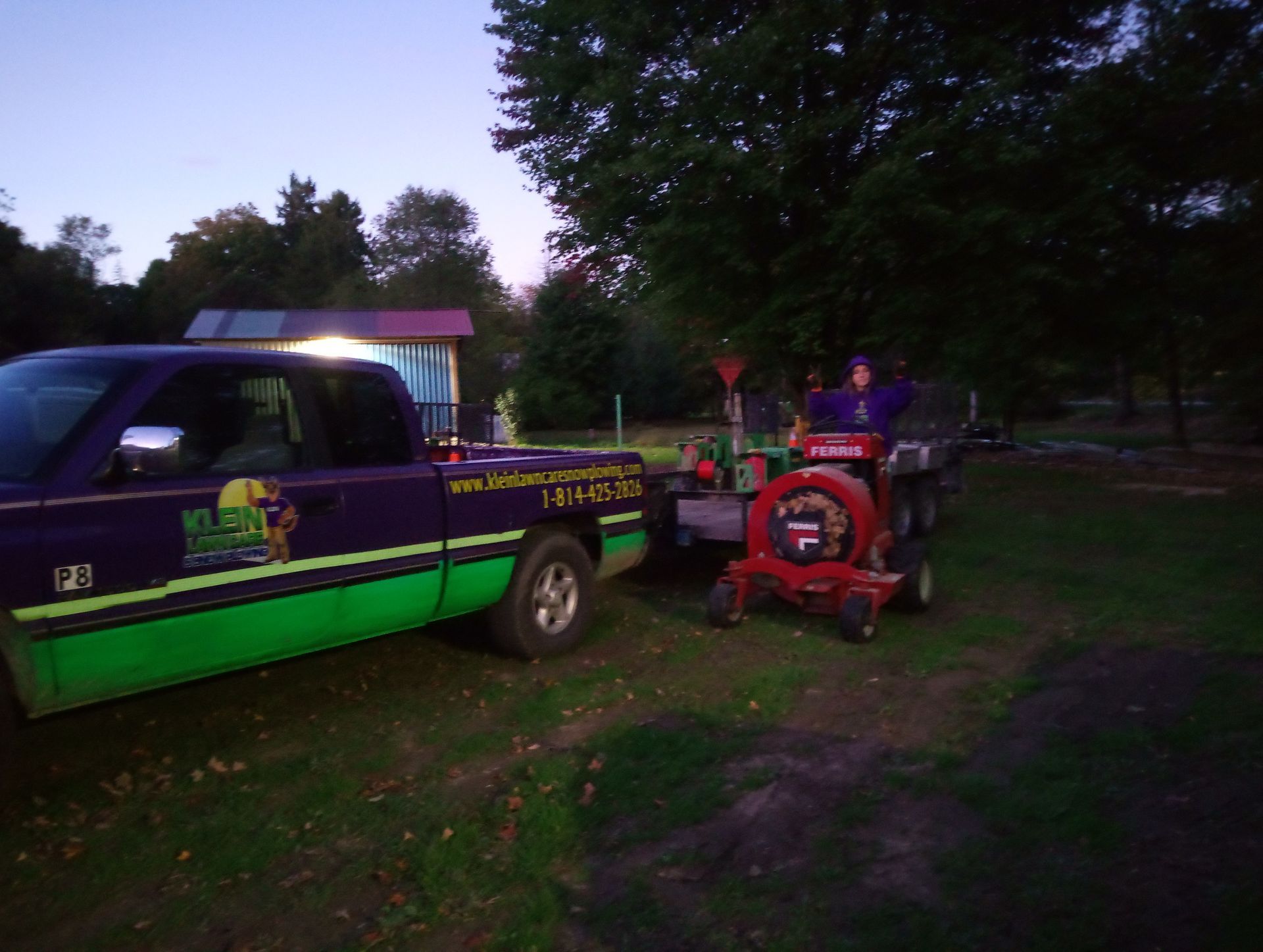 A man is driving a tractor next to a purple truck