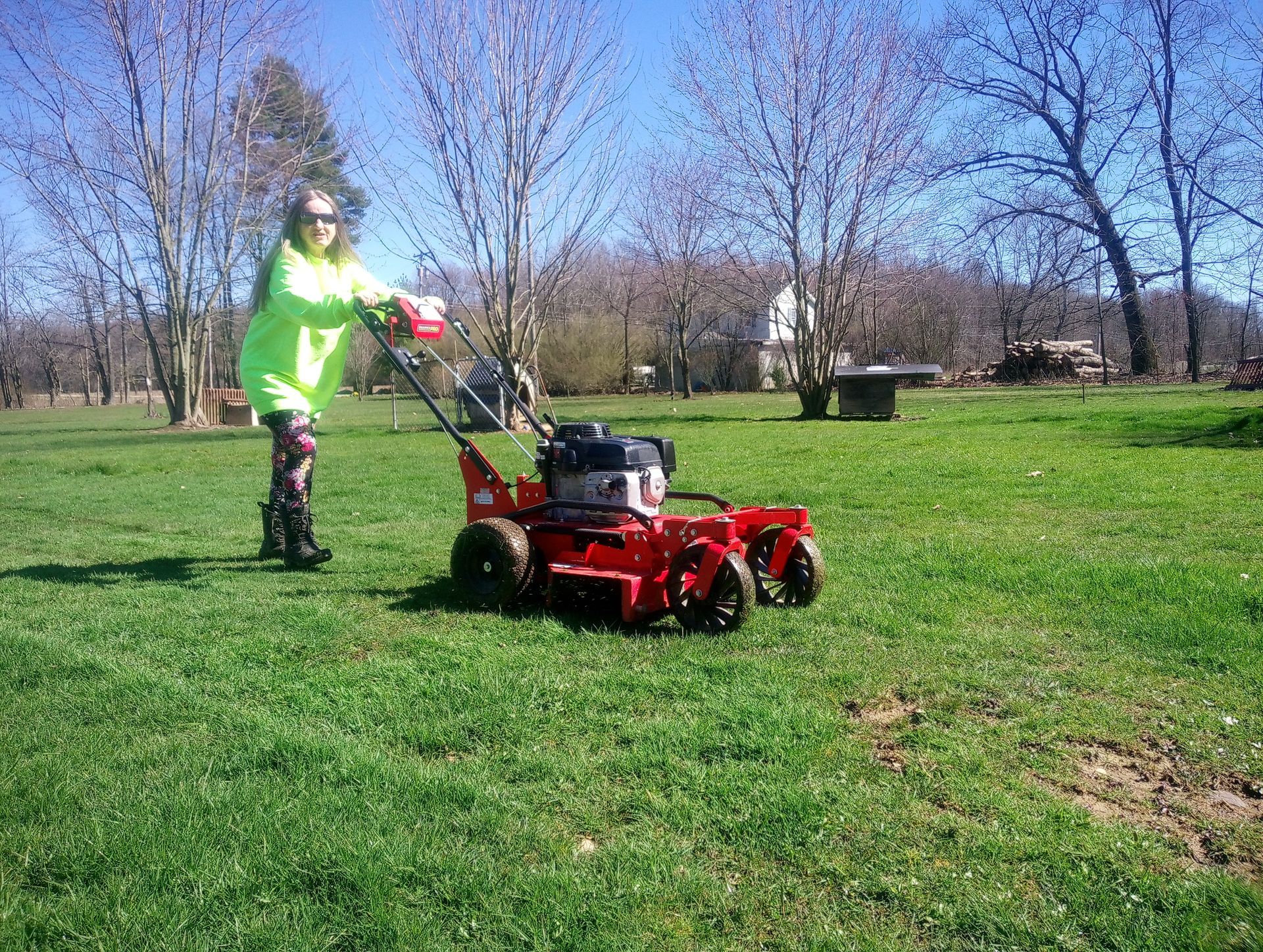 A woman is using a red lawn mower to cut the grass